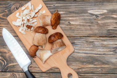 Tahta masanın üzerinde kısmen doğranmış bir grup lezzetli beyaz mantar. Ormandaki doğal mantar. Vejetaryen yemek malzemeleri. Porcini mantarları ve tahta tahta tahta manzaralı bıçak. Gün ışığı.