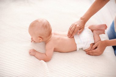 Bebek masajı. Bebek 5 aylık, karnının üstünde yatıyor ve emeklemeye çalışıyor. Anne, çocuğun gelişimi için ona sırt masajı yapar. Çocuk jimnastiği ve egzersizleri..
