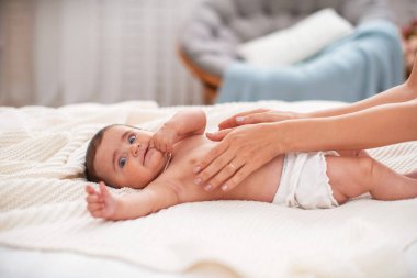 Bebek masajı. Kolik sırasında bebeğin karnına masaj yapan bir masör. Sırtüstü uzanmış yeni doğmuş kolik bir bebek, annesinin eli karnında, sancısı geçmesine yardım ediyor..