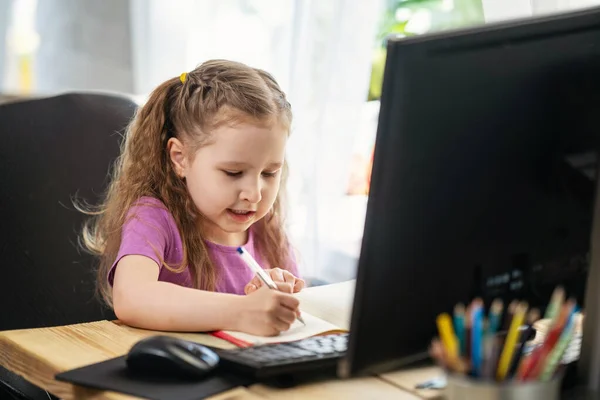 女の子は家で勉強するのにコンピューターを使う 子供は喜んで笑顔で遠隔で知識を受けます 電子学習のデジタル概念 流行中 隔離と自己分離 遠隔Eラーニング — ストック写真
