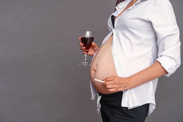 Smoking and alcoholism during pregnancy. pregnancy and cigarette Smoking. Harm to child\'s health . Premature birth. Close-up of a pregnant woman abandons bad habits.On a gray background. Copy space
