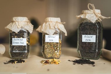 Masada üç farklı çay çeşidi bulunan kavanozlar, alternatif ilaçlar ve doğal yiyecekler var. Çay, demlenmek için, doğal kağıt kapaklı cam kavanozlarda saklanır. Aromatik bir çay karışımı..