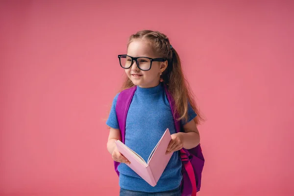 Hermosa Niña Sonriente Con Gafas Sosteniendo Libro Con Una Bolsa — Foto de Stock