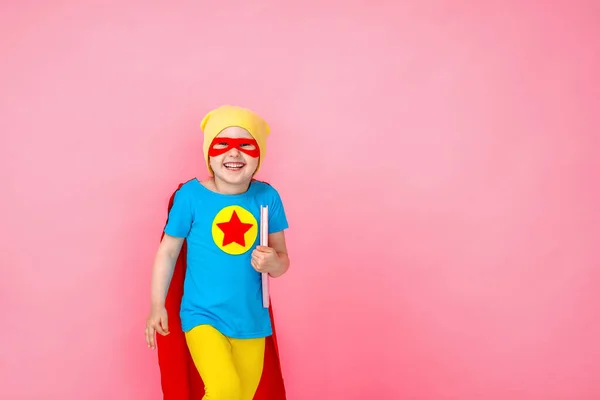 Glad Barn Spelar Superhjälte Med Bok Händerna Rosa Bakgrund Glad — Stockfoto