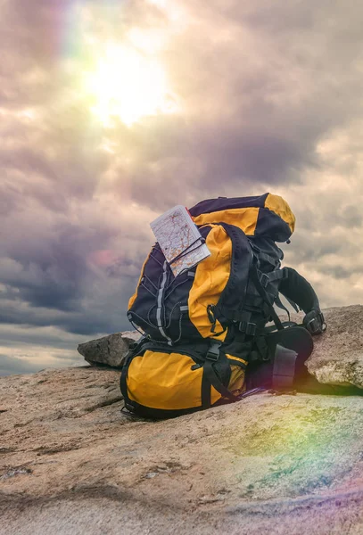 Mochila naranja acostada en una piedra Senderismo, senderismo, fondo, en la cima de una montaña, rocas, cielo, naturaleza, orientación al mapa, éxito, logro . — Foto de Stock