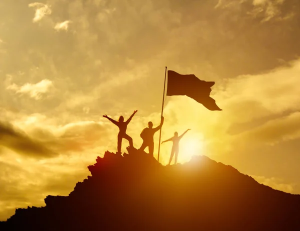 Alto sucesso, família três silhueta, pai de mãe e criança segurando bandeira da vitória no topo da montanha, mãos para cima . — Fotografia de Stock