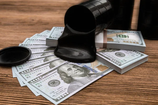 Oil flows out of the barrel into a hundred dollar bills background