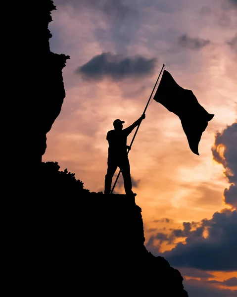 Silhueta de um homem no topo de uma montanha com uma bandeira nacional de vitória ! — Fotografia de Stock