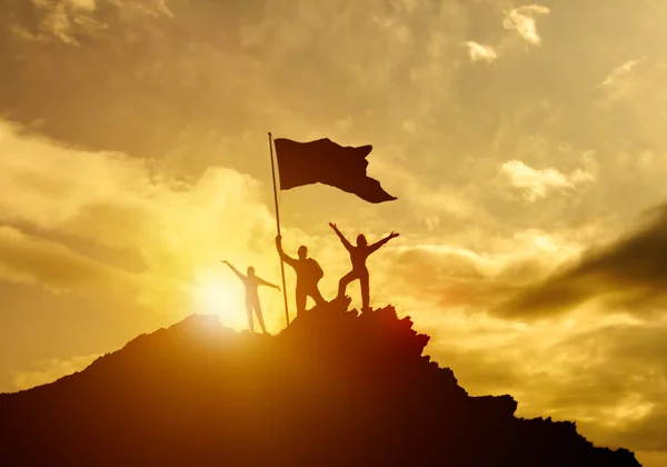 High success, family three silhouette, father of mother and child holding flag of victory on top of mountain, hands up. A man on top of a mountain.