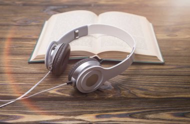 Ses kitabı konsepti. Kulaklıklar ve eski kitaplar ahşap masanın üzerinde.. 