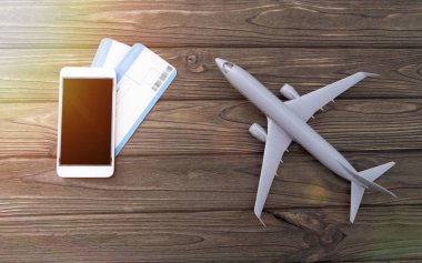 Siyah arka planlı akıllı telefon, uçak biletleri, tahta arka planda uçak.