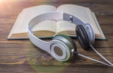 Ses kitabı konsepti. Kulaklıklar ve eski kitaplar ahşap masanın üzerinde.. 