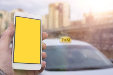 Yakın çekim el taksi rezervasyon bir cep telefonu bir araba ve bir şehir, arka planda tutan bir adam. Temiz sarı smartphone ekran reklam tasarımı için yukarı alay.
