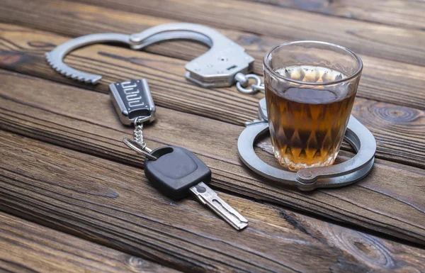 Sarhoşken araba kullanmayı kavramsallaştır. Kelepçe, bir bardak alkol, araba anahtarları..