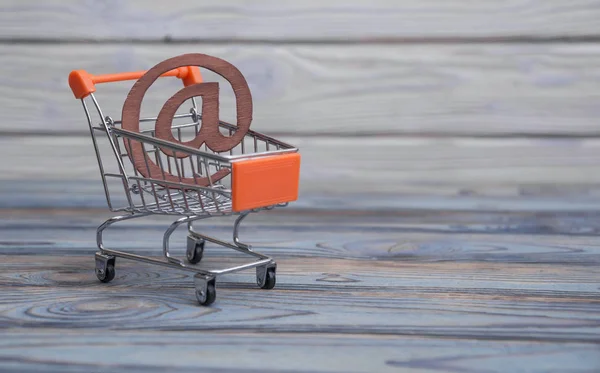 an email symbol, shopping cart on a wood board background. The idea of buying online. depicting the concept of e-shopping or e-commerce