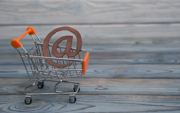 an e-mail symbol, shopping cart on a wood board background. The idea of buying online. depicting the concept of e-shopping or e-commerce