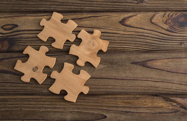 Placing a piece of the puzzle on a textured old wooden table. Conceptual work in the team and cooperation. idea of business