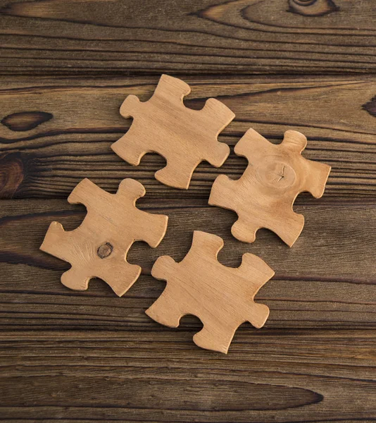 Placing a piece of the puzzle on a textured old wooden table. Conceptual work in the team and cooperation. idea of business