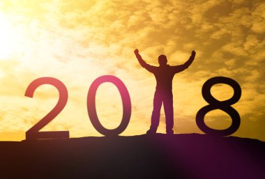 Bir adam silüeti bir dağın tepesinde ve güneş ışığı ile metin 2018 işaret mutlu yeni yıl takvim tatil kavramı üzerinde ellerini. Yeni yıl Noel