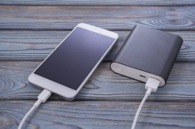 Enerji banka ile şarj telefon. ahşap masa arka plan. Güç yakasında alan derinliği.