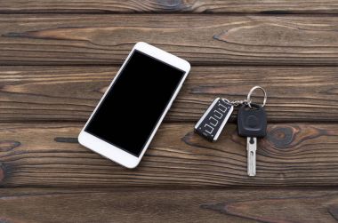 Smartphone, arabanın anahtarlarını ahşap bir masa arka plan üzerinde