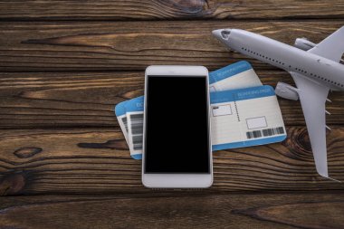 Akıllı telefon, biletler, tahta bir arka planda uçak..