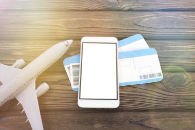 bir smartphone ile beyaz bir ekran, iki uçak biletleri, ahşap bir masa bir uçakta. yolculuk