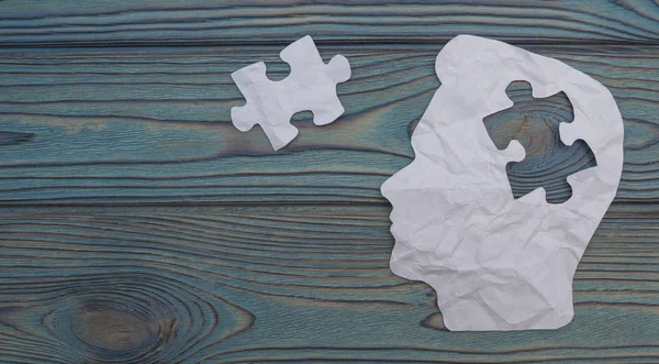 Composite image of paper in the form of a head on a wooden background. Detail of puzzles from the head. Business concept. Ideas, decision making.