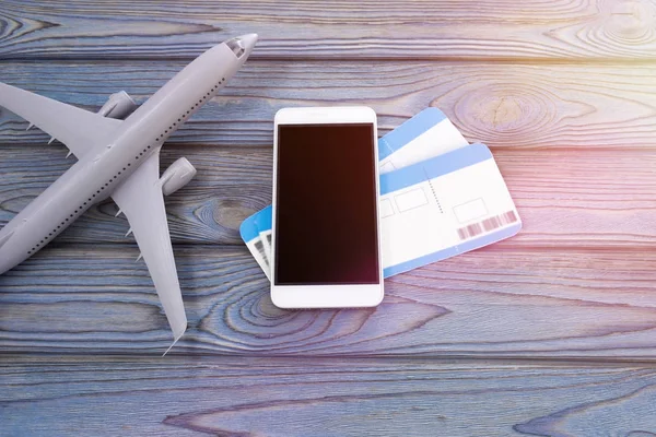 smartphone, two plane tickets on a wooden background. journey.