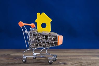 Mavi bir arka plan üzerinde bir alışveriş arabası sarı evde kavramının. Fikir: Kiralama, gayrimenkul satan bir ev satın almak. İpotek. Konut kredisi.