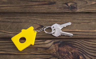 Sarı şekilli ev Anahtarlık zinciri ahşap doku arka plan üzerinde üzerinde anahtarla. Fikir: Kiralama, gayrimenkul satan bir ev satın almak. İpotek. Konut kredisi.