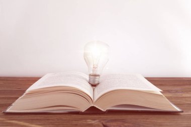 kitap, elektrikli ampul ahşap bir masa üzerinde. entelektüel faaliyet. fikir.