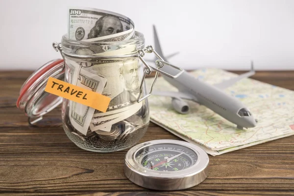 Budget Travel concept. Travel money savings in a glass jar with toy aircraft on world map and compass. to save for the trip