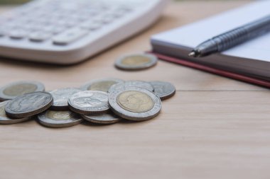 Mali rapor iş. Closeup madeni para ve banknot ve hesap makinesi, ahşap arka plan üzerinde kitap.