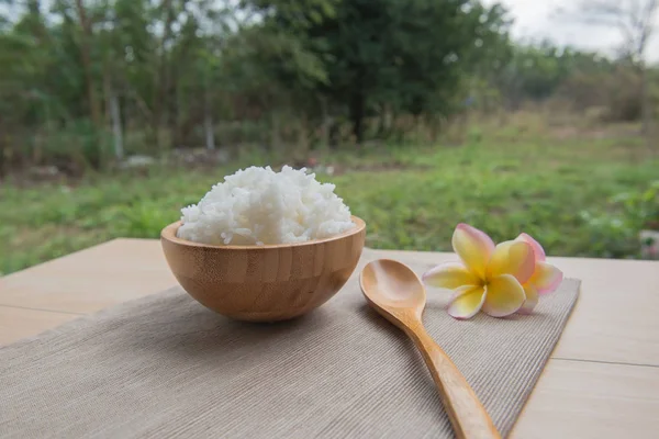 Arroz cocido en un tazón de madera y cuchara sobre un fondo de madera . — Foto de Stock