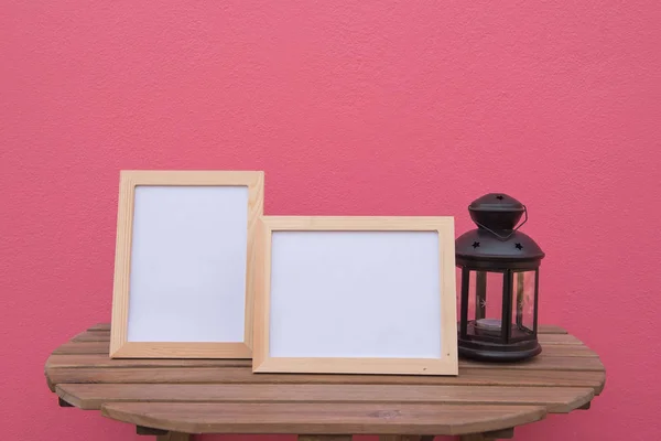 Фото Рамка на деревянном фоне и фонарь на розовом фоне  . — стоковое фото