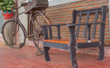 Turuncu tuğla duvarlar ve eski bisiklet üzerinde ahşap sandalye.