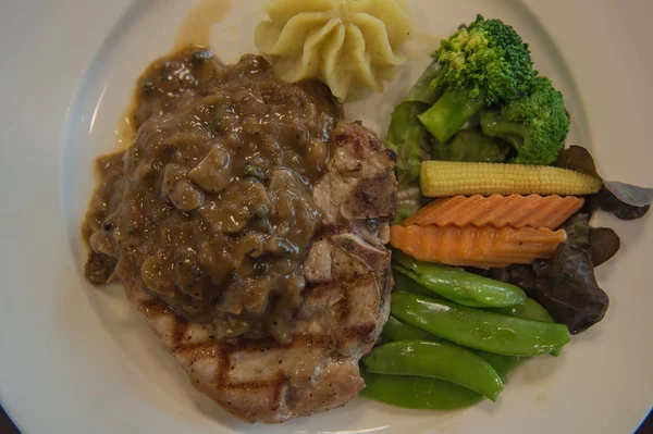 Domuz eti biftek ve beyaz tabakta sebze . 