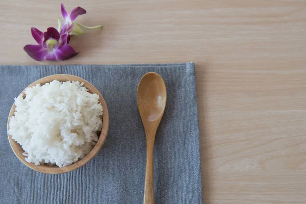 Arroz cocido en un tazón de madera y cuchara sobre un fondo de madera . — Foto de Stock