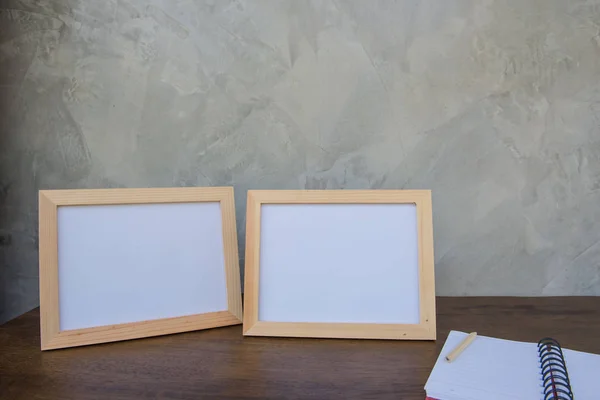 Две фотографии Рамка на деревянном столе и книга на фоне серой стены  . — стоковое фото