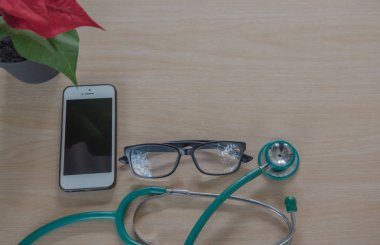 Üstten Görünüm stetoskop tıbbi ekipman ve ahşap arka plan üzerinde telefon.