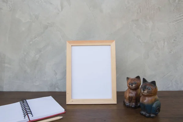 Фото Рамка на деревянном столе и книга и игрушечная кошка — стоковое фото