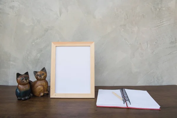 Фото Рамка на деревянном столе и книга и игрушечная кошка — стоковое фото