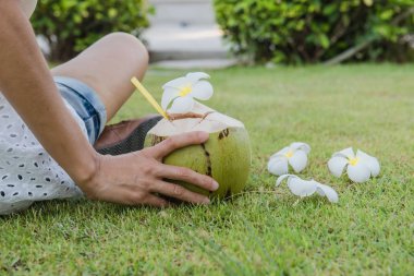 Hindistan cevizi ve kadınlar yeşil çimlerde dinlenir.