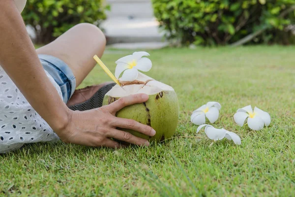 Hindistan cevizi ve kadınlar yeşil çimlerde dinlenir.