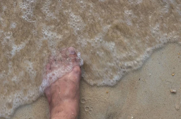 Üstten görünüm ve sol ayak, kum ve dalgalar deniz yaz aylarında adam — Stok fotoğraf