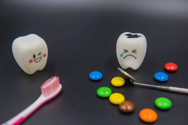 Modelo Bonito brinquedos dentes e doces coloridos na odontologia em um fundo preto — Fotografia de Stock