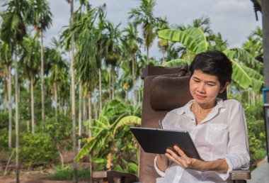 Bahçedeki ahşap sandalye tablet bilgisayarı kullanan kadın 