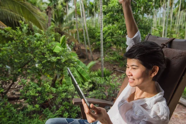 Donne che utilizzano tablet computer su sedie in legno in giardino — Foto Stock