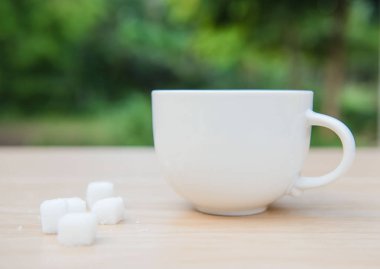 Ahşap bir masa üzerinde closeup beyaz Kupası ve küp şeker 